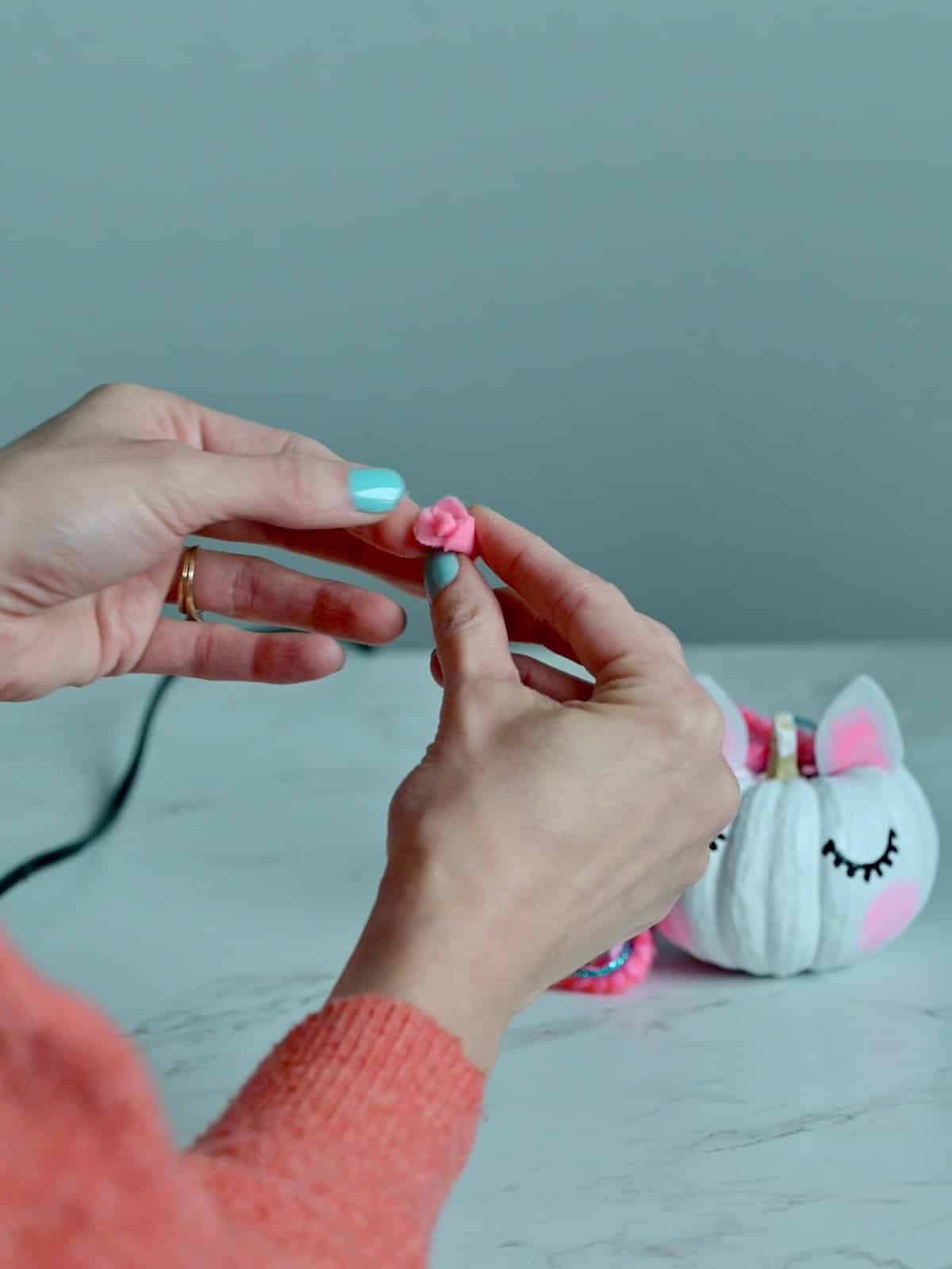 Hands showing felt rolled together to make a felt flower.