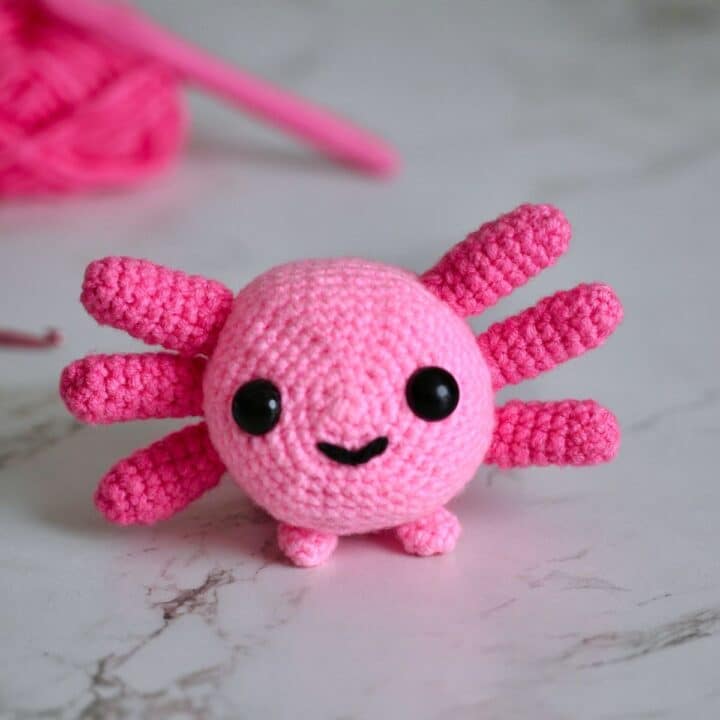 A bright small Axolotl Amigurumi made with light pink and dark pink yarn.