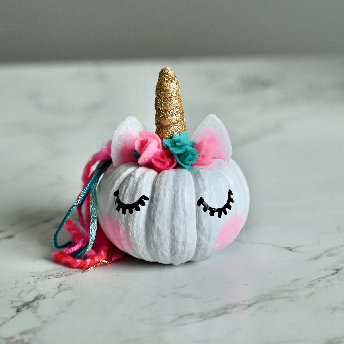 A finished mini painted unicorn pumpkin.